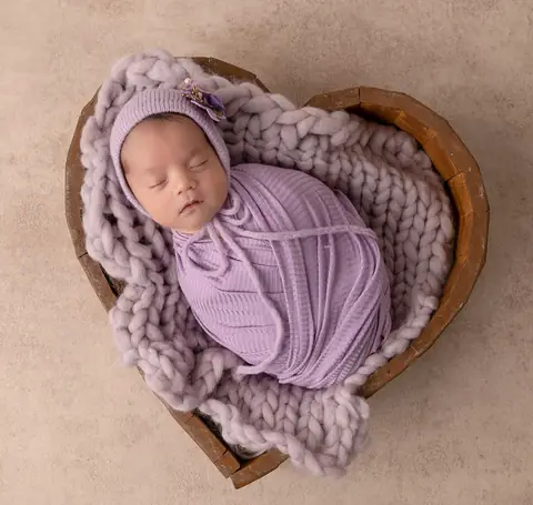 Recién nacida envuelta en lila dentro de una canasta en forma de corazón