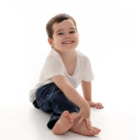 Niño sentado en el piso de un estudio blanco