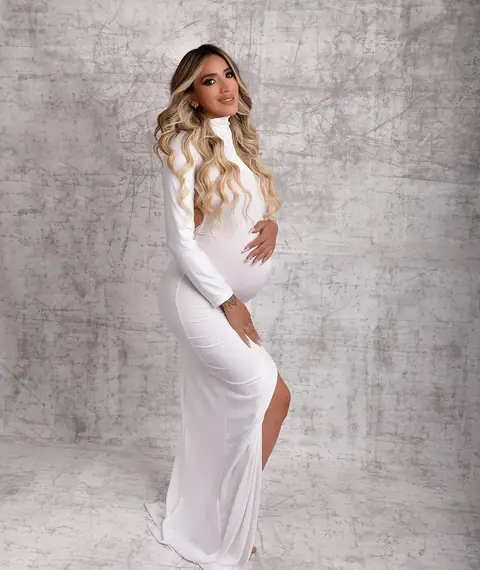 Embarazada con vestido blanco mirando hacia un costado